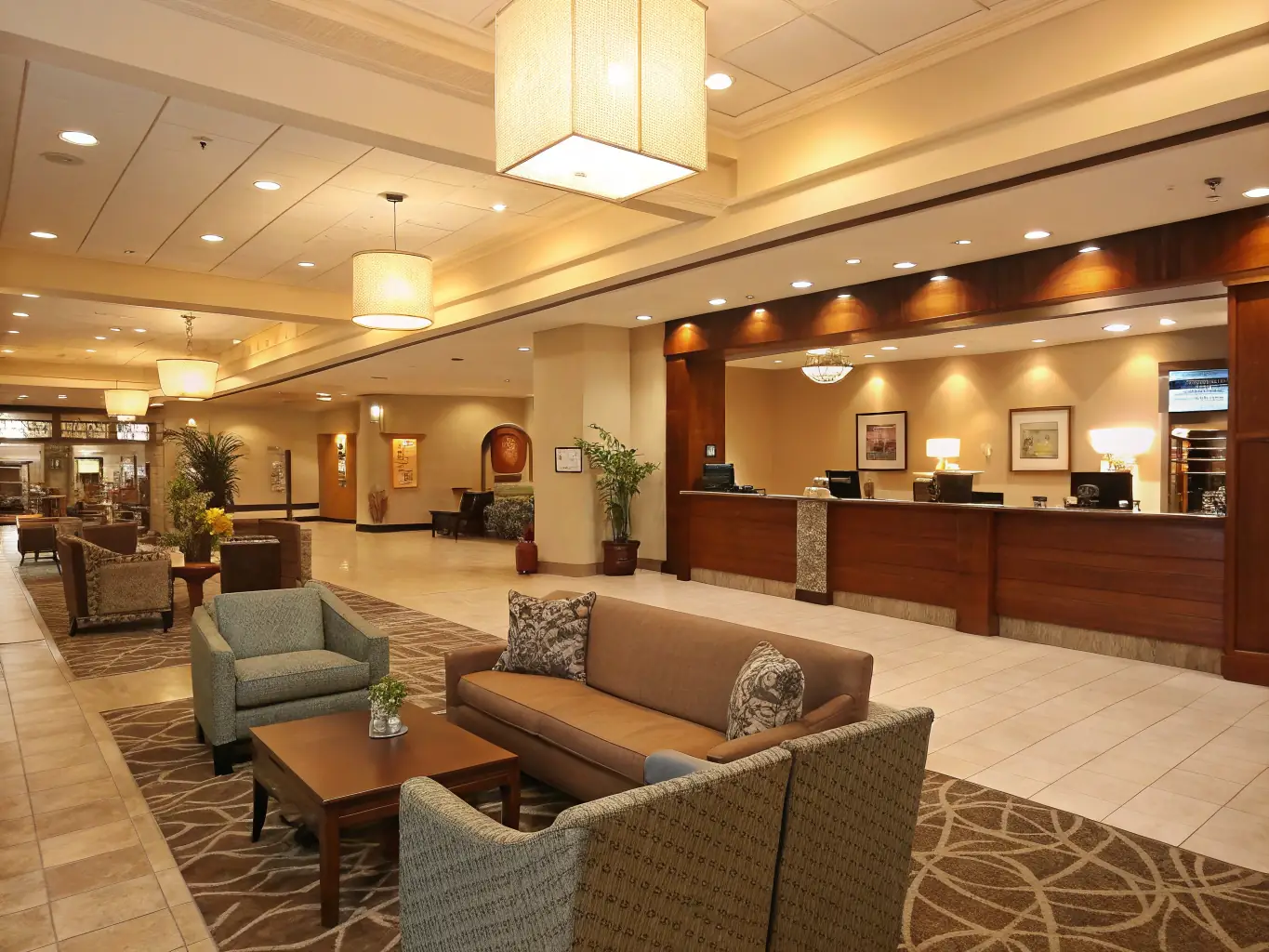 A modern hotel lobby with comfortable seating and a charging station visible in the background.