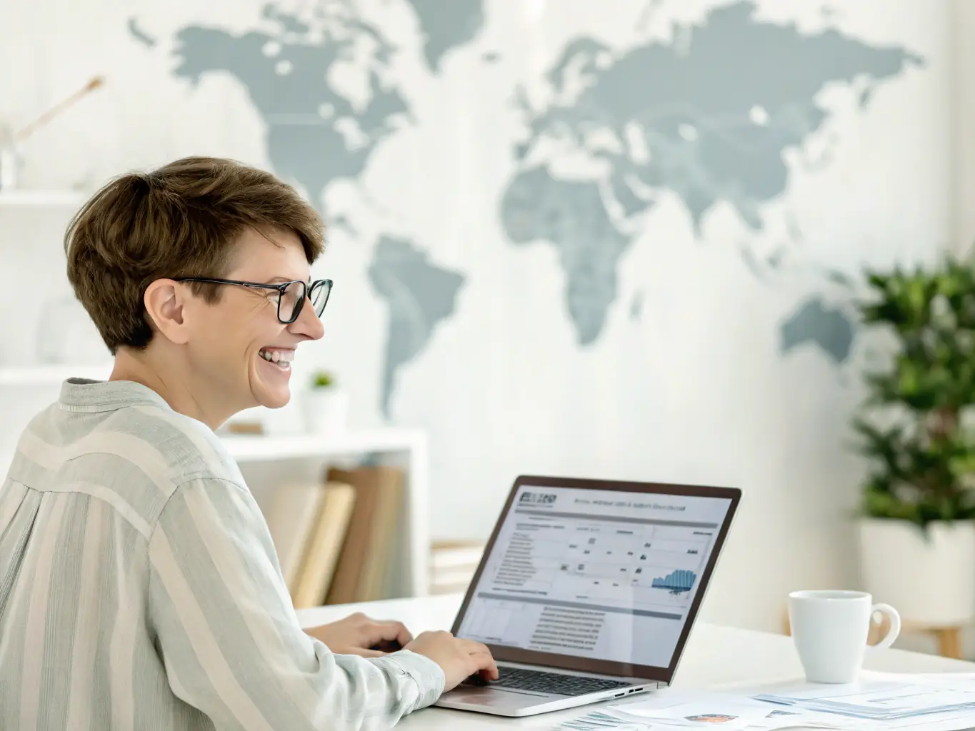 A person working on a laptop with accounting software, surrounded by financial documents and charts.