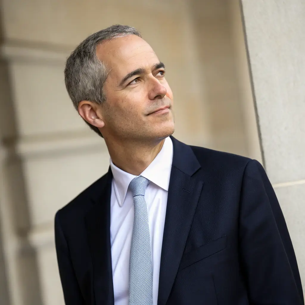 Ethan has short dark hair, wears a tie, and has a persuasive smile.