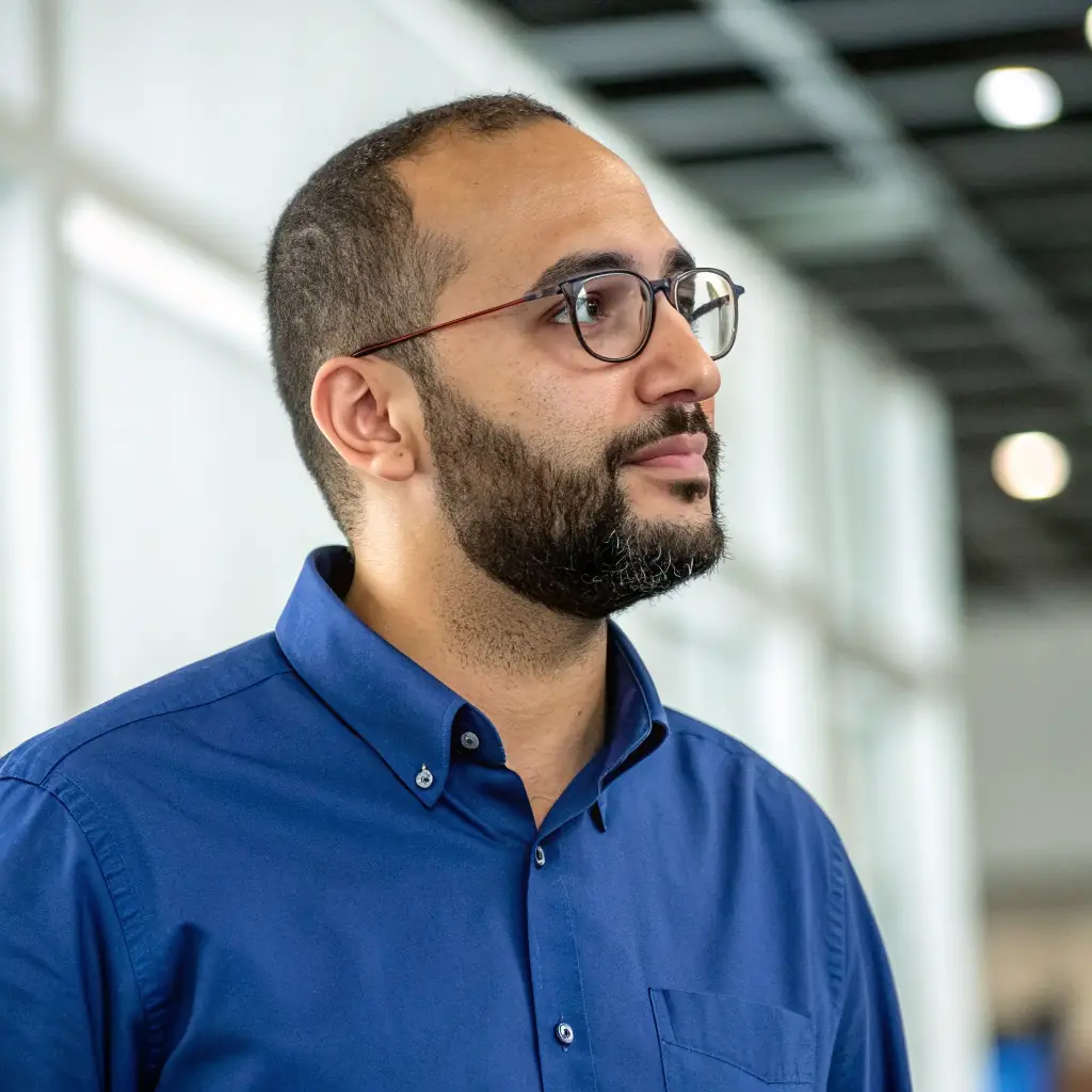 Bob has a neatly trimmed beard, wears a blue shirt, and has a focused expression.