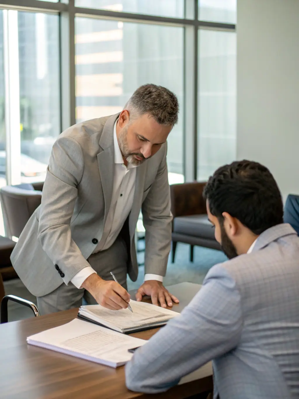 A professional photo of a Trustpoint attorney meeting with a Latino client, reviewing documents and discussing their case with empathy and understanding.