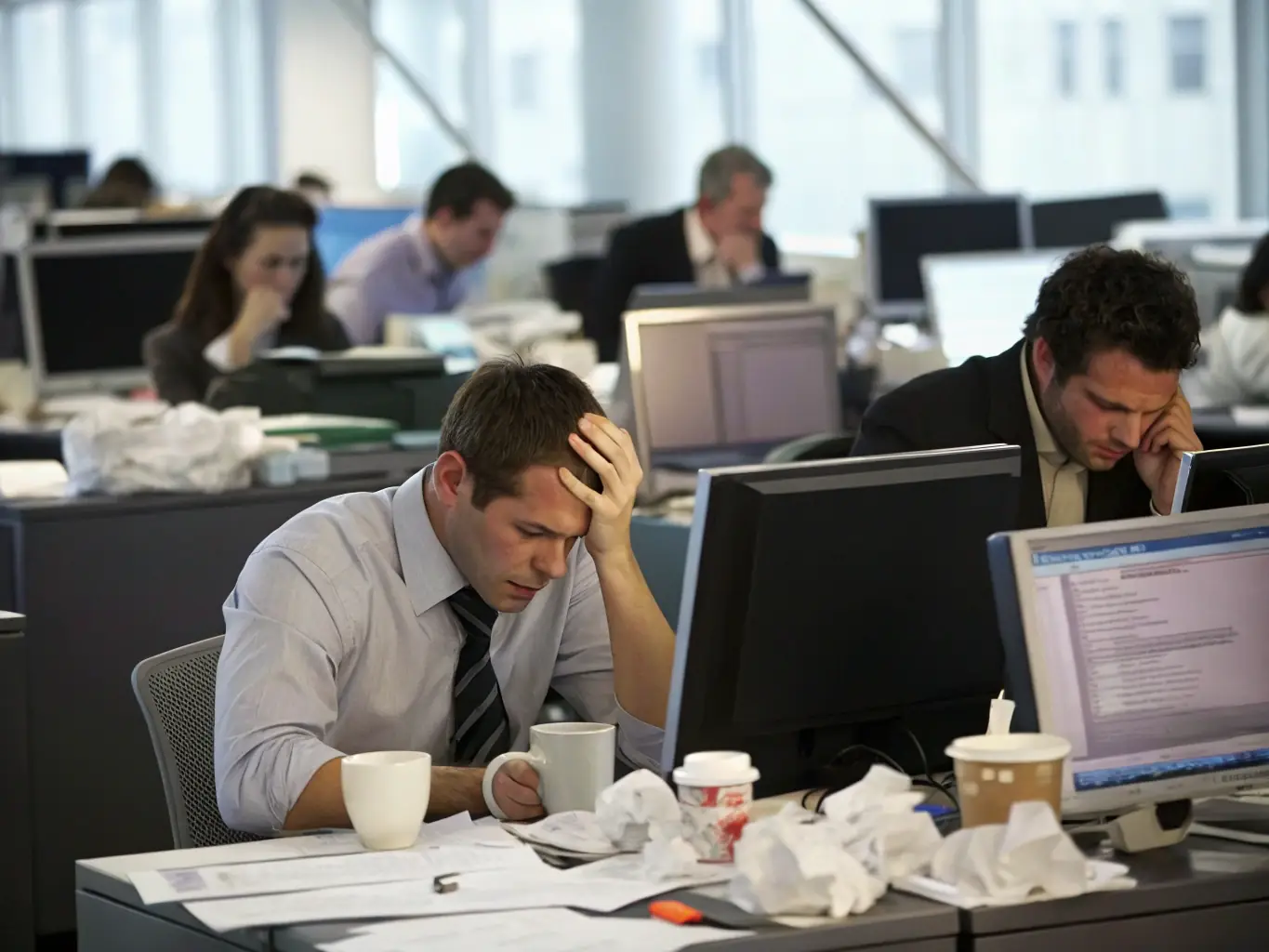 A group of stressed-out people trying to juggle multiple tasks at once, symbolizing the challenges of managing IT assets without proper ITAM-disciplines.