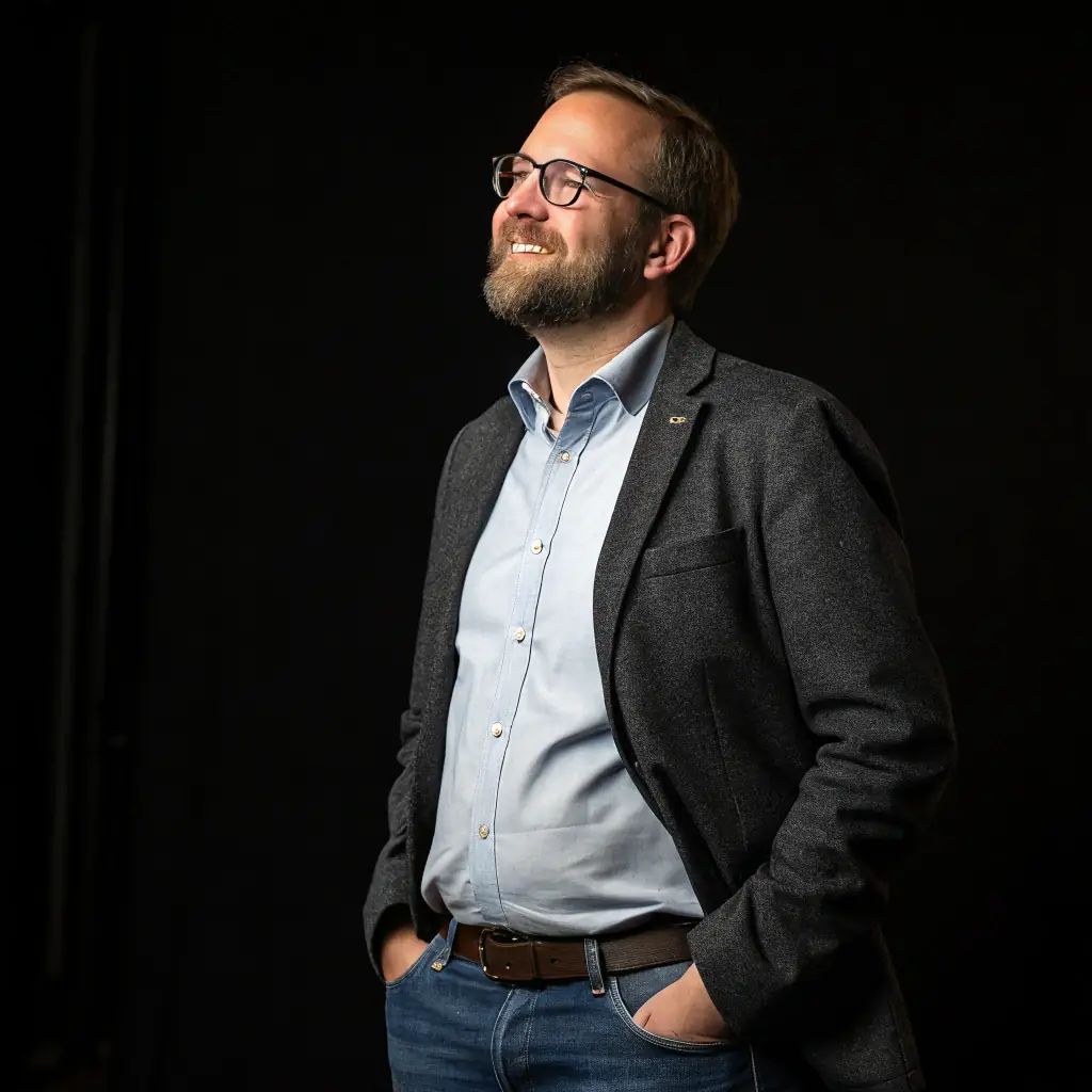 A man with glasses and a neatly trimmed beard wearing a suit.