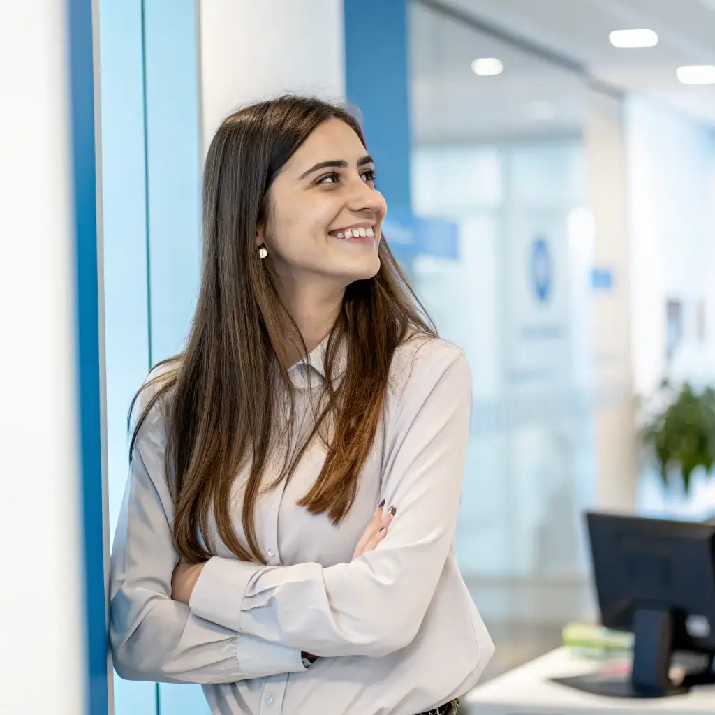 A woman with long brown hair, wearing a blue sweater and jeans.
