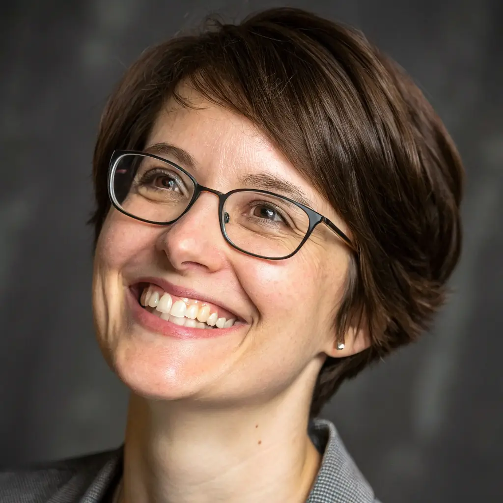 Dr. Sharma has short, curly brown hair and wears glasses, often seen with a thoughtful expression.