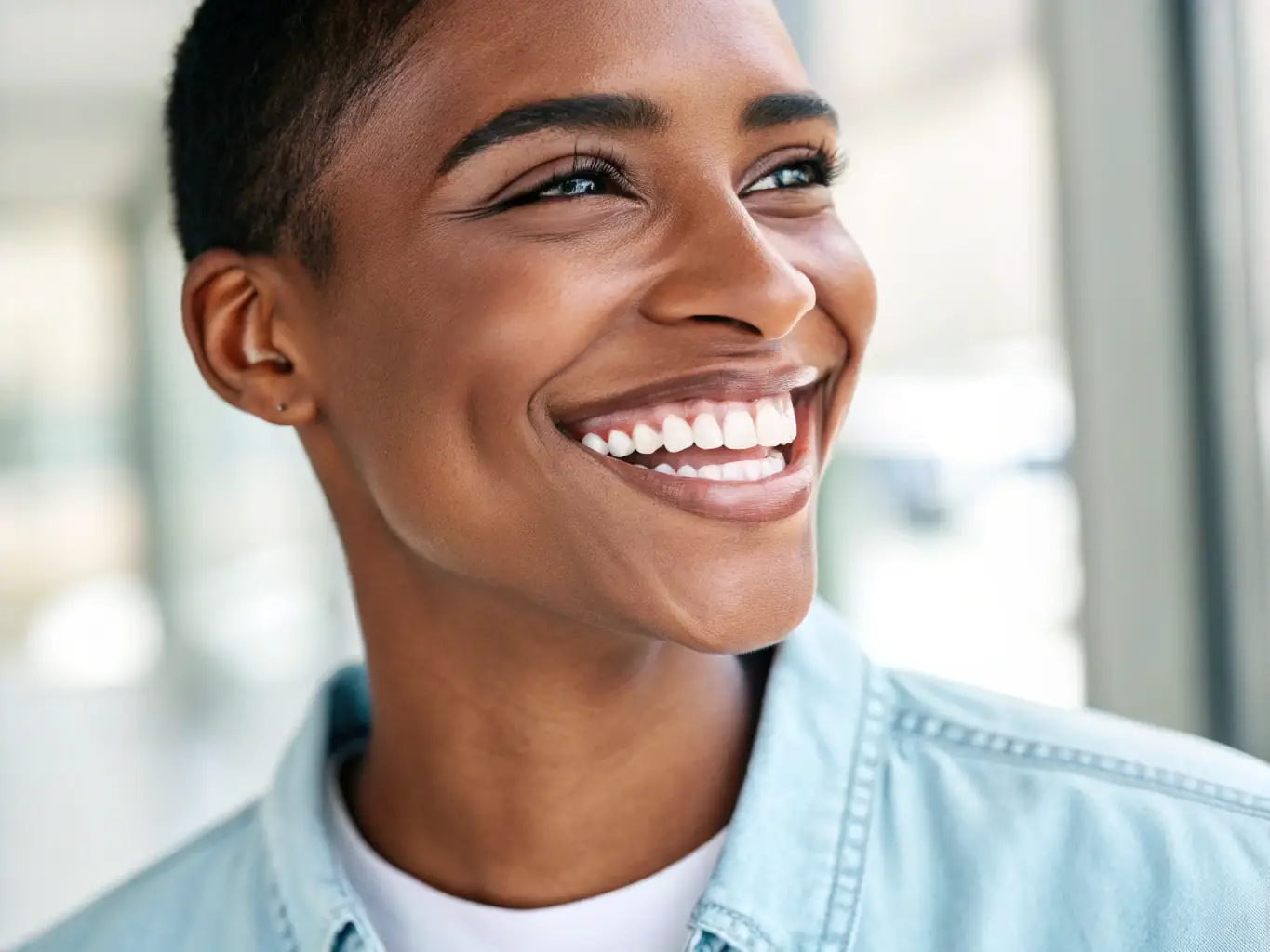 A person smiling brightly after undergoing a professional teeth whitening treatment at a dental clinic. The focus is on the radiant, white teeth, highlighting the effectiveness of the whitening procedure.